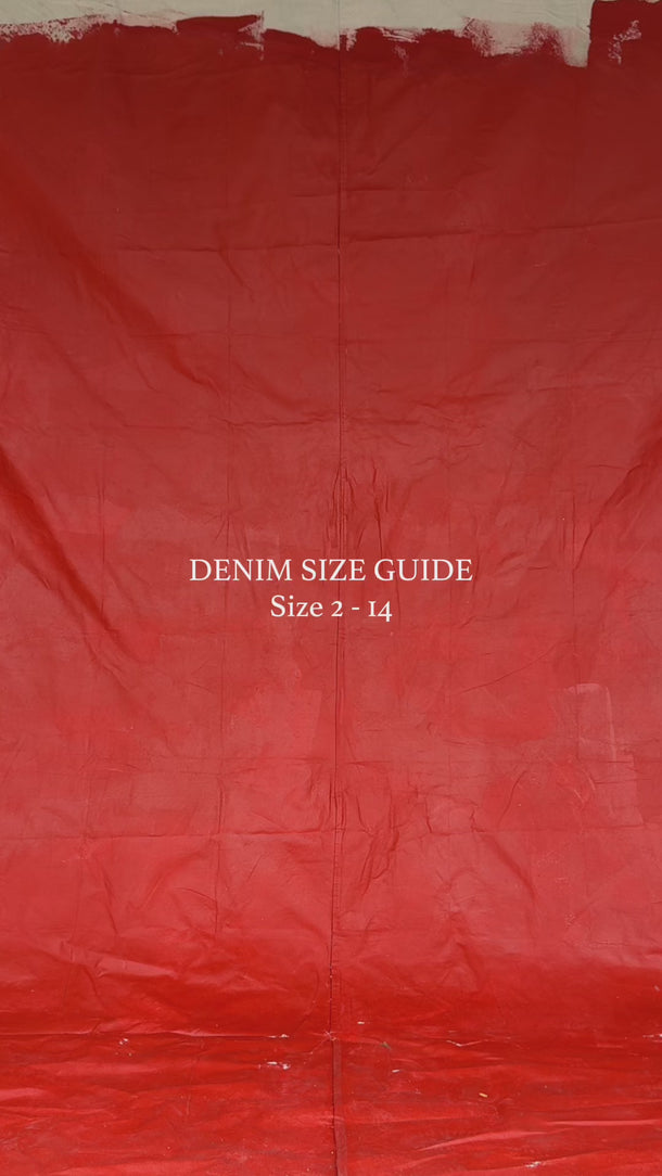 Video of various women wearing different size jeans in front of a red backdrop to showcase fit. Sizes 2 to 14 shown.
