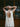Person wearing a white dress with an open back, standing in front of a wooden door.